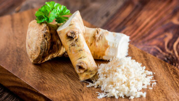 Meerrettich: Stücke von Meerrettichwurzel und geriebener Meerrettich auf einem Holzbrett.